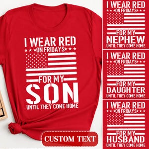 May include: A red short-sleeved t-shirt featuring a white graphic print of an American flag and the text I WEAR RED ON FRIDAYS FOR MY SON UNTIL THEY COME HOME. The design includes stars and stripes elements with bold white lettering.