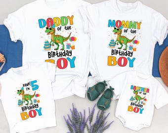 May include: A set of four white t-shirts featuring a dinosaur graphic and the text "Daddy of the Birthday Boy", "Mommy of the Birthday Boy", "Brother of the Birthday Boy", and "Rawr! I'm 5 Birthday Boy".