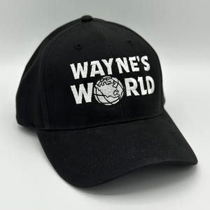 May include: Black baseball cap with the text "WAYNE'S WORLD" embroidered in white, along with a globe graphic. The cap has a curved brim and a structured fit.