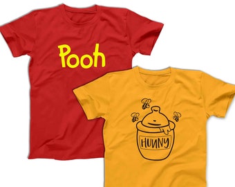 Könnte beinhalten: Ein rotes Kurzarm-T-Shirt mit dem gelben Schriftzug Pooh und ein goldenes Kurzarm-T-Shirt mit einer schwarzen Strichzeichnung eines Honigtopfes mit der Aufschrift HUNNY und drei kleinen Bienen, die um den Topf auf der Vorderseite fliegen.