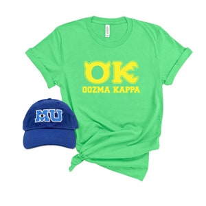 May include: A green t-shirt with yellow text that reads "OK OOZMA KAPPA". A blue baseball cap with a white eye and the letters "MU" in white is also pictured.