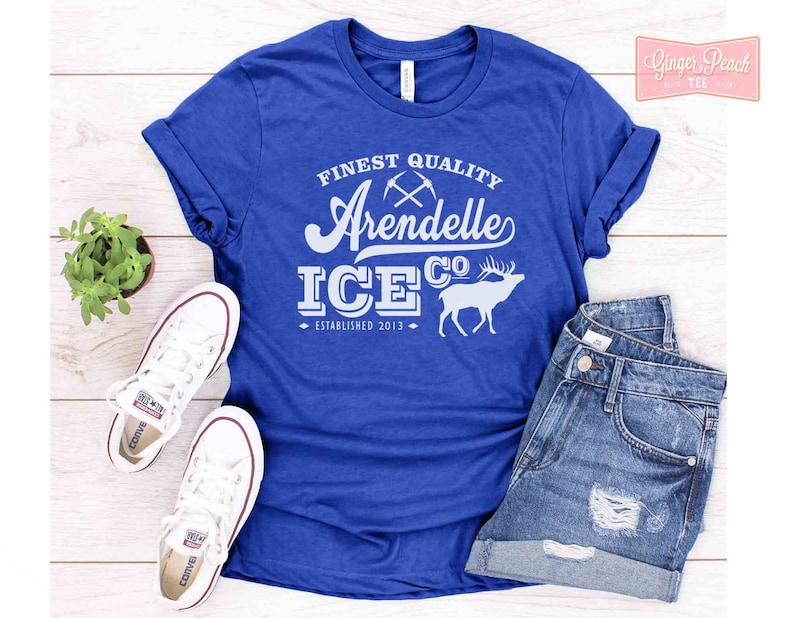 Puede incluir: Una camiseta azul real con un dise&ntilde;o gr&aacute;fico blanco que dice "Finest Quality Arendelle Ice Co. Established 2013" con una silueta blanca de un reno.