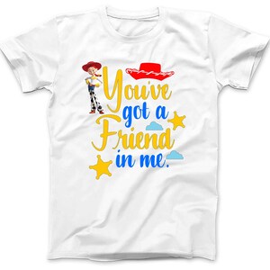 May include: White t-shirt with a cartoon image of Woody from Toy Story. The shirt has the text "You've got a friend in me." in blue and yellow lettering.