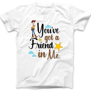 May include: White t-shirt with a brown cartoon image of Woody from Toy Story. The text "You've got a friend in me." is printed in brown on the shirt.
