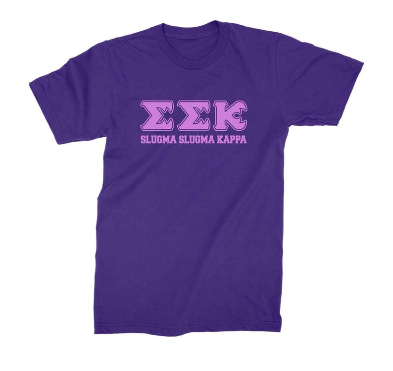 Peut inclure: T-shirt violet avec un motif de lettres grecques roses qui dit "&Sigma;&Sigma;&Kappa;" et "SLUGMA SLUGMA KAPPA" en lettres roses.