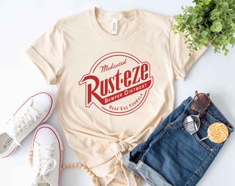 May include: A beige t-shirt with a red circle logo that says "Medicated Rusteze Bumper Ointment Rear End Formula".