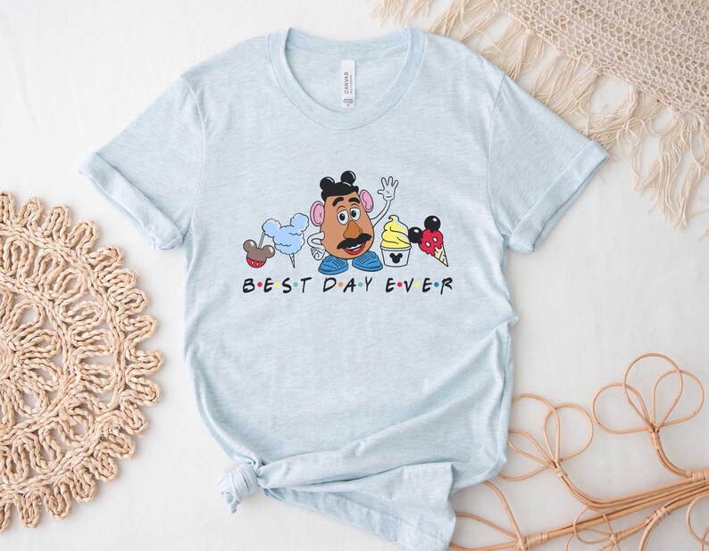 May include: Light blue t-shirt with a graphic of Mr. Potato Head and other Disney characters. The text "BEST DAY EVER" is printed below the graphic.