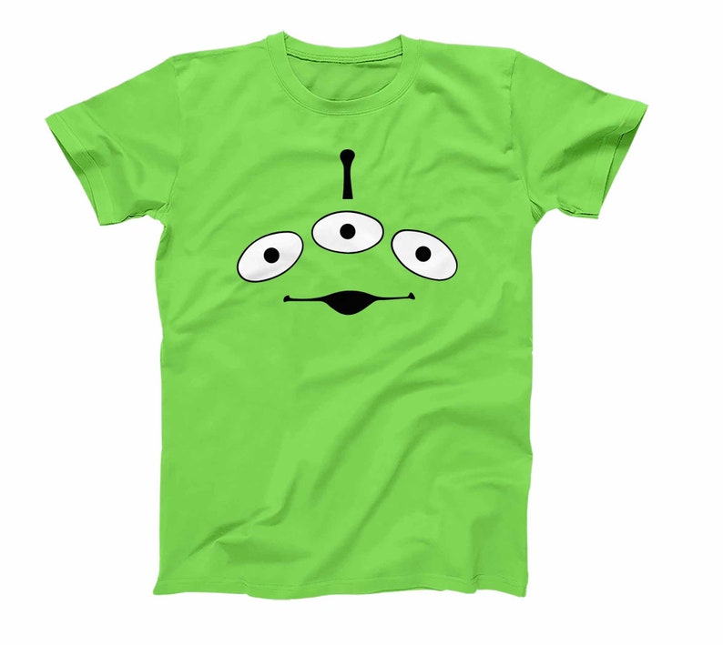 May include: A green t-shirt with a black alien face design. The alien has three eyes and a small mouth.