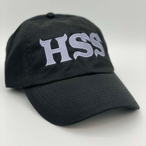 May include: A black baseball cap with a white embroidered logo that says "HSS" in a stylized font.