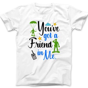 May include: White t-shirt with a green paratrooper, a blue cloud, a yellow star, and green army man graphic. The text on the shirt reads "You've got a Friend in Me."