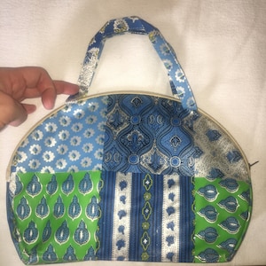 Op de afbeelding: Een blauwe en groene patchwork stoffen toilettas met een ritssluiting en een bovenste handvat. De tas is ongeveer 20 cm breed.