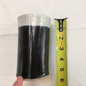 May include: A handmade ceramic tumbler with a two-tone design. The top third is white, the bottom two-thirds are dark blue. The tumbler is approximately 15 cm tall.