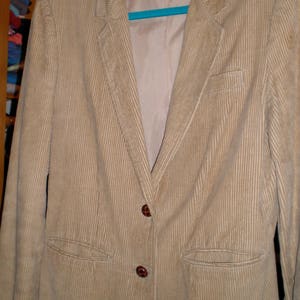 May include: A beige corduroy blazer with two brown buttons and a label that reads "Priorities" on the front.