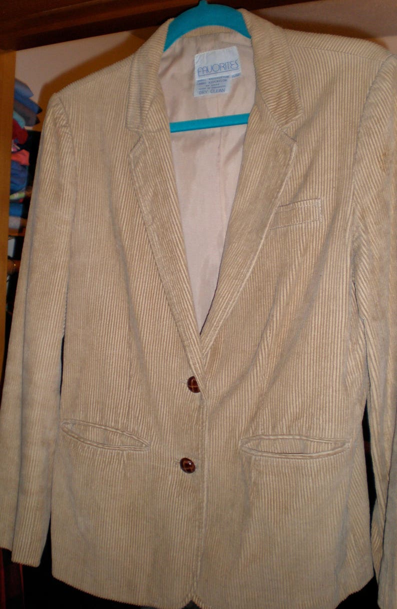 May include: A beige corduroy blazer with two brown buttons and a label that reads "Priorities" on the front.