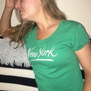 May include: A green t-shirt with a white "New York" graphic printed on the front.
