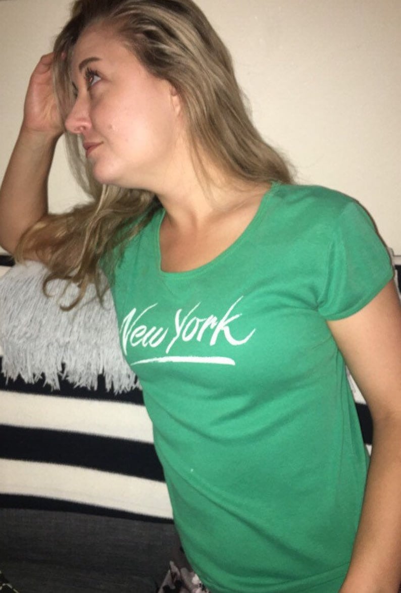 May include: A green t-shirt with a white "New York" graphic printed on the front.