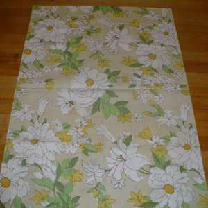 Puede incluir: Una hoja de papel de regalo beige con un patr&oacute;n floral. El patr&oacute;n presenta flores blancas con hojas verdes sobre un fondo beige.