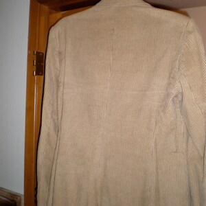 May include: A tan corduroy blazer hanging on a wooden door.