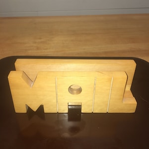 May include: Wooden mail holder with the word "MAIL" carved into it. The holder is made of light brown wood and has a slot for mail.