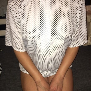 May include: A white blouse with a black polka dot pattern. The blouse has a button-up front and short sleeves.