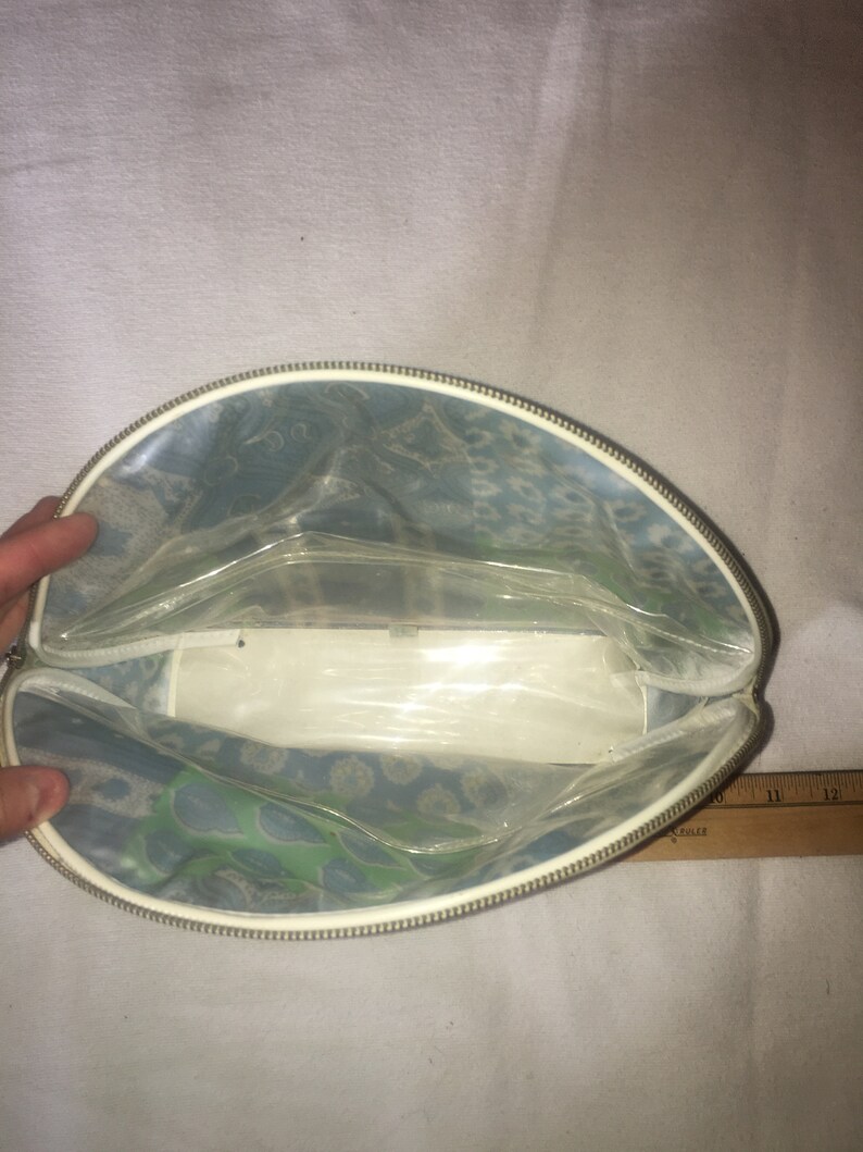 Op de afbeelding: Een doorzichtige, met een rits afsluitbare tas met een blauw en groen bloemenpatroon. De tas is open en leeg.
