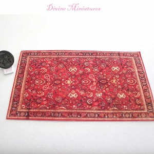 May include: A red and gold patterned rug with a detailed floral design. The rug is perfect for a dollhouse or miniature setting.