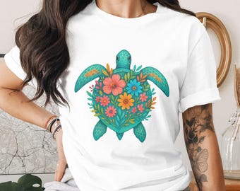 以下が含まれることがあります： 白のTシャツ。ターコイズ色のウミガメのデザイン。カメの甲羅は、ピンク、オレンジ、青の花の鮮やかな花の配置で飾られています。このシャツは快適でカジュアルなスタイルです。