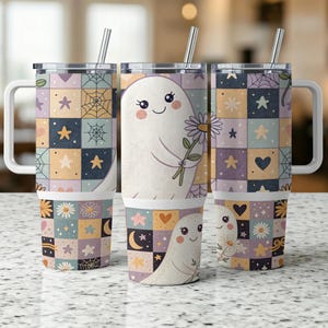 May include: Three white travel mugs with a patchwork design featuring stars, hearts, and flowers. One mug has a cartoon ghost holding a daisy. Each mug has a silver straw and a white handle.