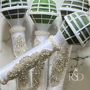 Peut inclure: Quatre supports de bouquet floraux blancs avec des inserts en mousse verte et des embellissements en strass d&eacute;coratifs.