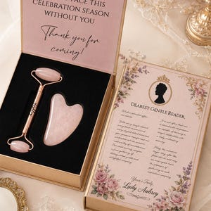 May include: A rose quartz facial roller and a heart-shaped gua sha tool set in a gold-trimmed box. The box lid features the text: I SIMPLY COULD NOT BARE TO FACE THIS CELEBRATION SEASON WITHOUT YOU. Thank you for coming! The other side displays a letter.