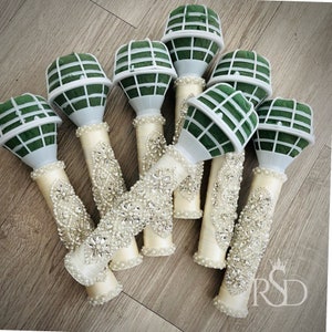 Peut inclure: Sept supports de mousse florale blancs avec des inserts en mousse verte, d&eacute;cor&eacute;s de ruban de satin ivoire et de strass. Les supports sont dispos&eacute;s en grappe sur une surface en bois.