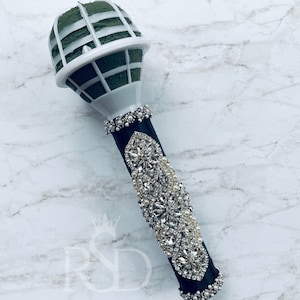Puede incluir: Un porta-bouquet en forma de micr&oacute;fono negro y blanco con un inserto de espuma floral verde. El porta-bouquet est&aacute; decorado con diamantes de imitaci&oacute;n y perlas.
