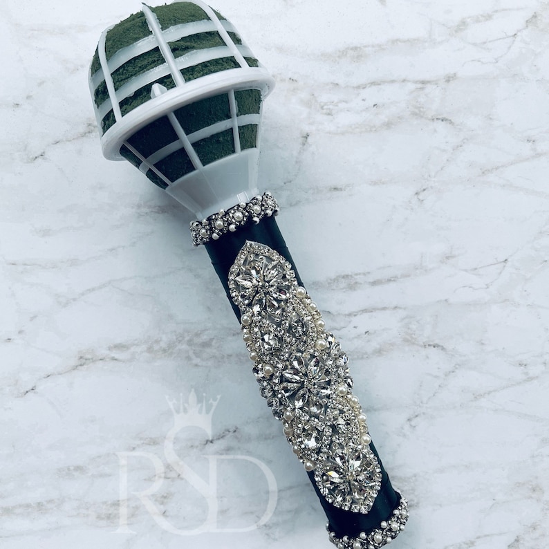 Puede incluir: Un porta-bouquet en forma de micr&oacute;fono negro y blanco con un inserto de espuma floral verde. El porta-bouquet est&aacute; decorado con diamantes de imitaci&oacute;n y perlas.