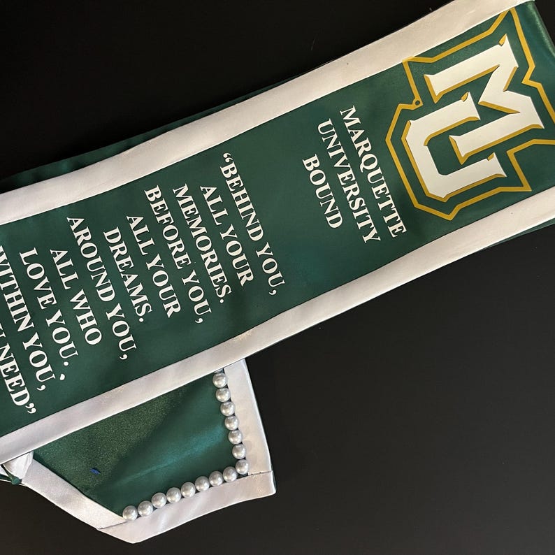 May include: Green and white graduation sash with the Marquette University logo and the text "Bound" and "Behind you, all your memories. Before you, all your dreams. Around you, all who love you. Within you, need."