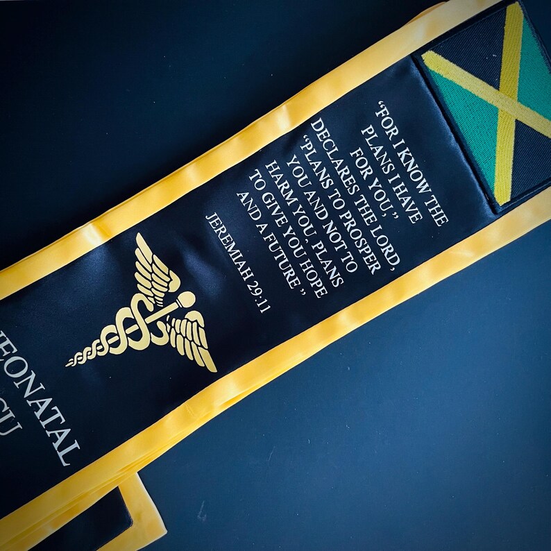 May include: Black and gold graduation sash with a medical symbol and the text "FOR I KNOW THE PLANS I HAVE FOR YOU," DECLARES THE LORD, "PLANS TO PROSPER YOU AND NOT TO HARM YOU, PLANS TO GIVE YOU HOPE AND A FUTURE." JEREMIAH 29:11"