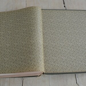 Op de afbeelding: Een gesloten boek met een groene en witte patroon op de omslag. Het boek ligt open op een licht houten oppervlak.