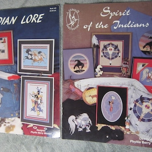 May include: Two cross-stitch pattern books featuring Native American themes. The book on the left is titled "Indian Lore" and the book on the right is titled "Spirit of the Indians". Both books feature colorful illustrations of Native American designs.