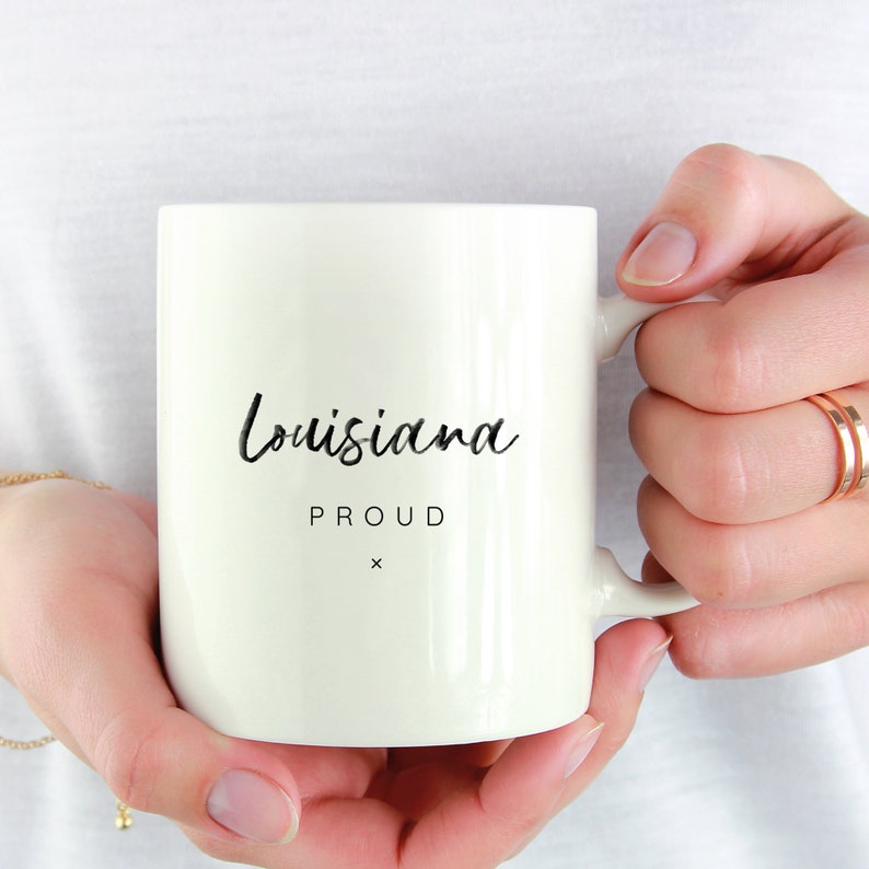 May include: White ceramic mug with black text that reads "Louisiana Proud" with a small "x" below the text.