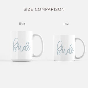 May include: Size comparison of two white ceramic mugs with the word "bride" written in light blue cursive. The mug on the left is 15 oz and the mug on the right is 11 oz.