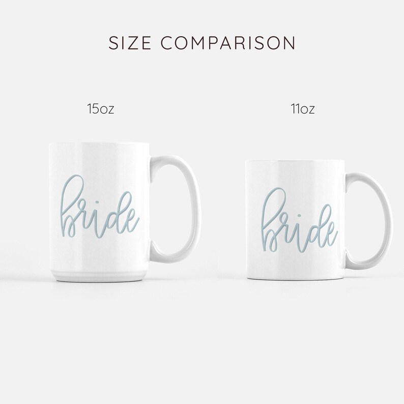 May include: Size comparison of two white ceramic mugs with the word "bride" written in light blue cursive. The mug on the left is 15 oz and the mug on the right is 11 oz.