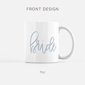 May include: White ceramic mug with a light blue cursive inscription that reads "bride". The mug is 11 ounces.