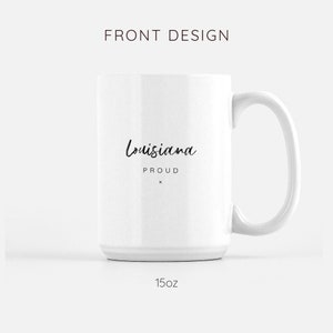 May include: White ceramic mug with a black handwritten design that says "Louisiana Proud" on the front. The mug is 15 ounces.
