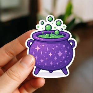 May include: A purple cauldron sticker with a bubbling green potion. The cauldron has a star pattern and is decorated with pink sparkles. Green bubbles float above the cauldron, creating a whimsical and magical design.