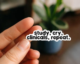 May include: A white sticker with black text that reads "study, cry, clinicals, repeat." The sticker is held between fingers in front of a blurred background with a plant in a dark blue pot.