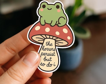 The Horrors Persist But So Do I Sticker | Cute Frog on Mushroom Vinyl Decal | Kawaii Cottagecore Waterproof Sticker | Spooky Quote