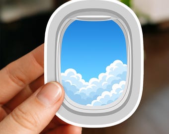 May include: A sticker featuring a stylized airplane window with a view of a blue sky and fluffy white clouds. The window frame is gray, and the sticker has a white border. The design evokes travel and aviation.