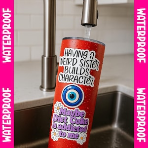 A red can with a sticker that says "Having a Weird Sister Builds Character" is being filled with water from a faucet.