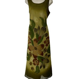 K&ouml;nnte beinhalten: Olivgr&uuml;nes &auml;rmelloses Kleid mit floralem Muster. Das Kleid hat gro&szlig;e braune und gr&uuml;ne Blumen mit gr&uuml;nen Bl&auml;ttern. Das Kleid wird auf einer wei&szlig;en Schaufensterpuppe pr&auml;sentiert.
