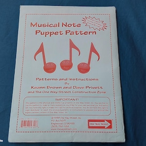 May include: A white paper featuring the title "Musical Note Puppet Pattern" and musical note illustrations. The pattern includes instructions by Keann Brown and Dave Privett, and is from One Way Street Construction Zone.