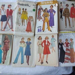 May include: A collection of vintage sewing patterns featuring various styles of women's clothing. The patterns are from the 1970s and include designs for dresses, trouser suits, and skirts. The patterns are in various colours, including red, blue, green, and yellow.
